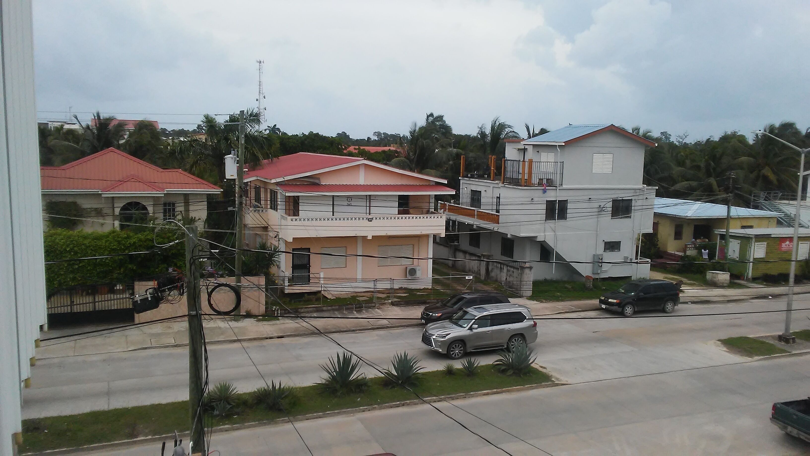 Una calle residencial con casas, una escalera visible y automóviles estacionados.