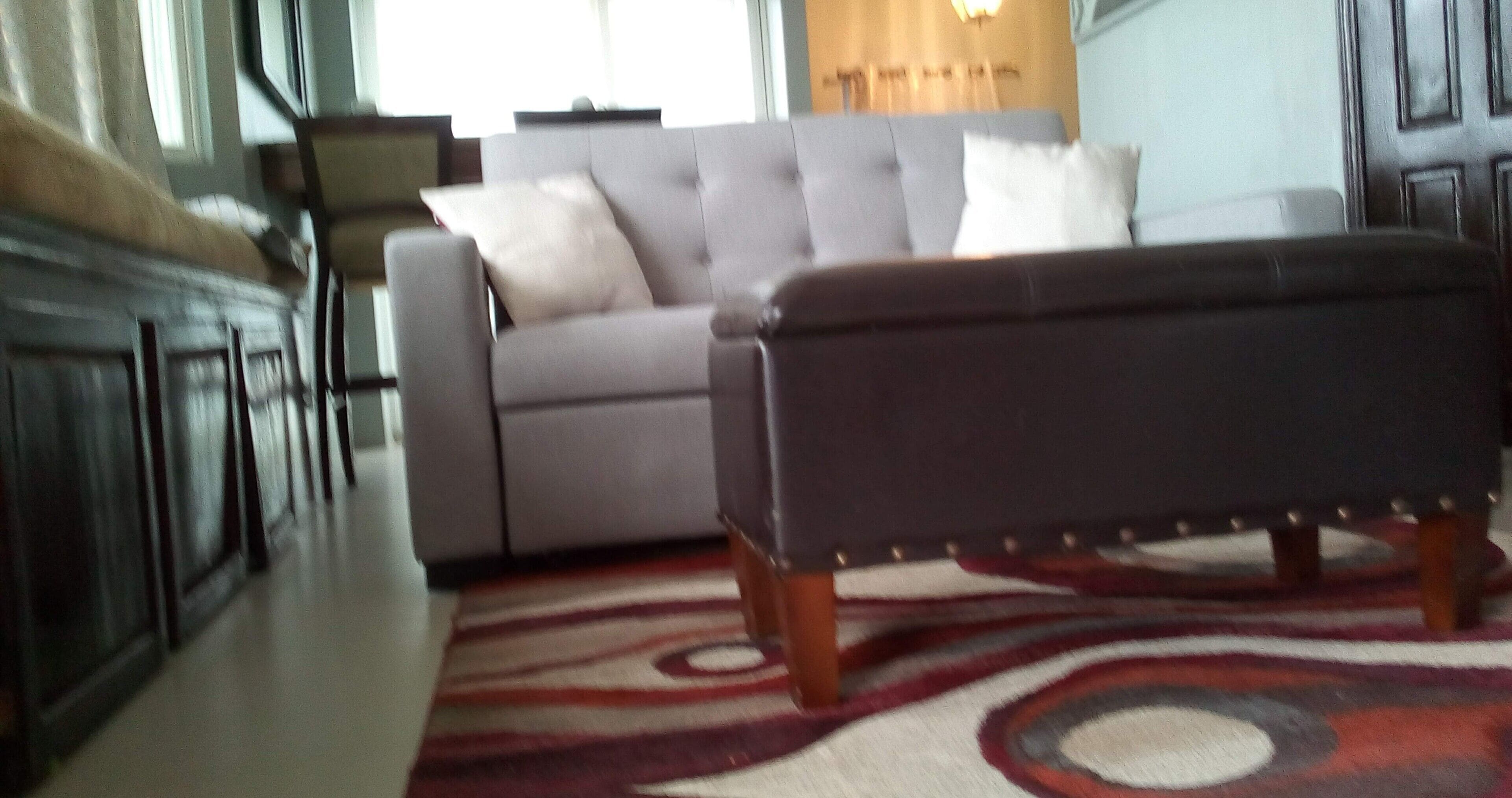A living room with a grey sofa, a dark bench, and a patterned rug.