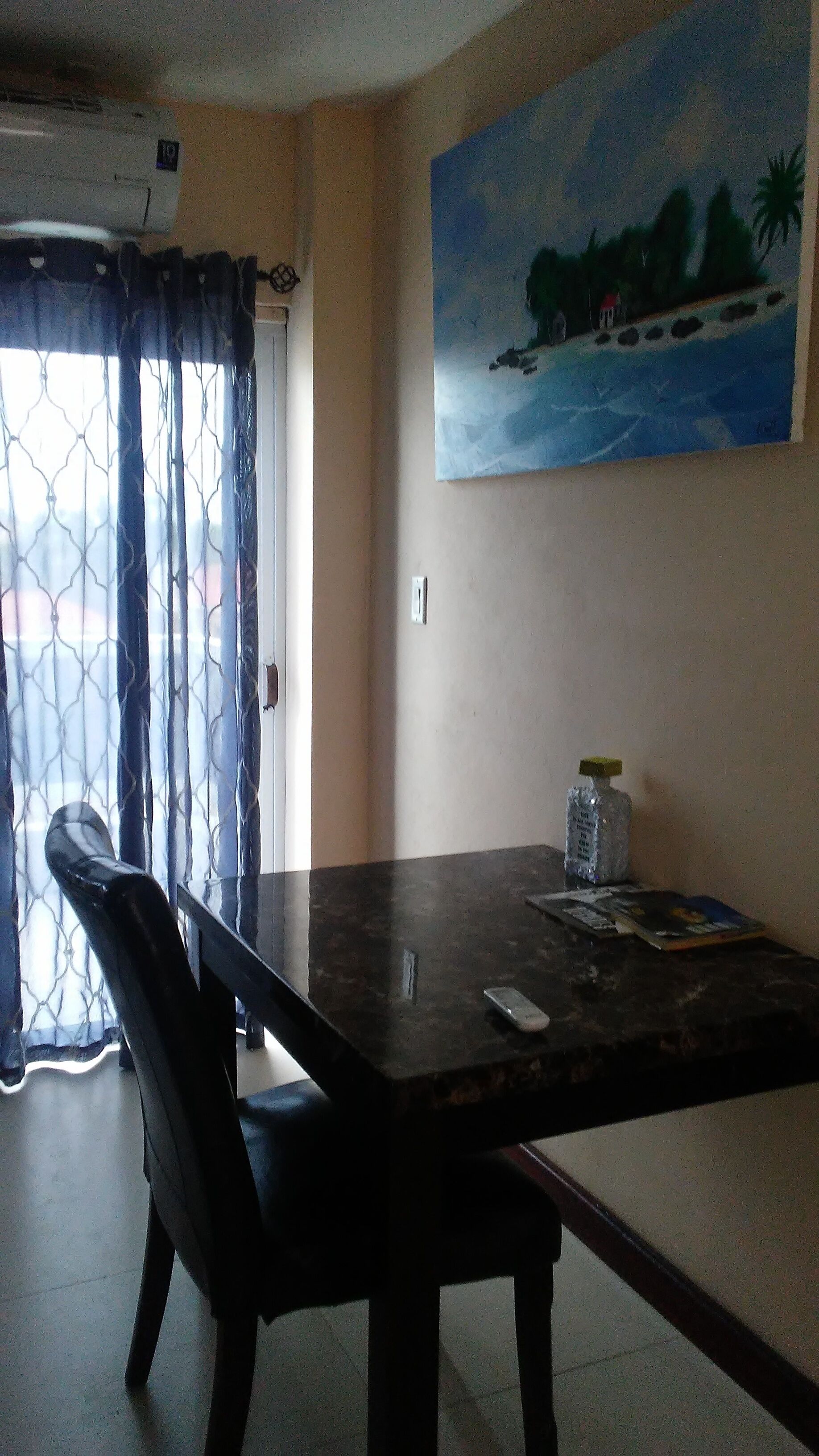 Un comedor con una mesa, sillas, un cuadro en la pared y una ventana con cortinas.