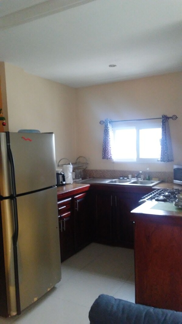 A compact kitchen with a refrigerator, stove, sink, and cabinets.