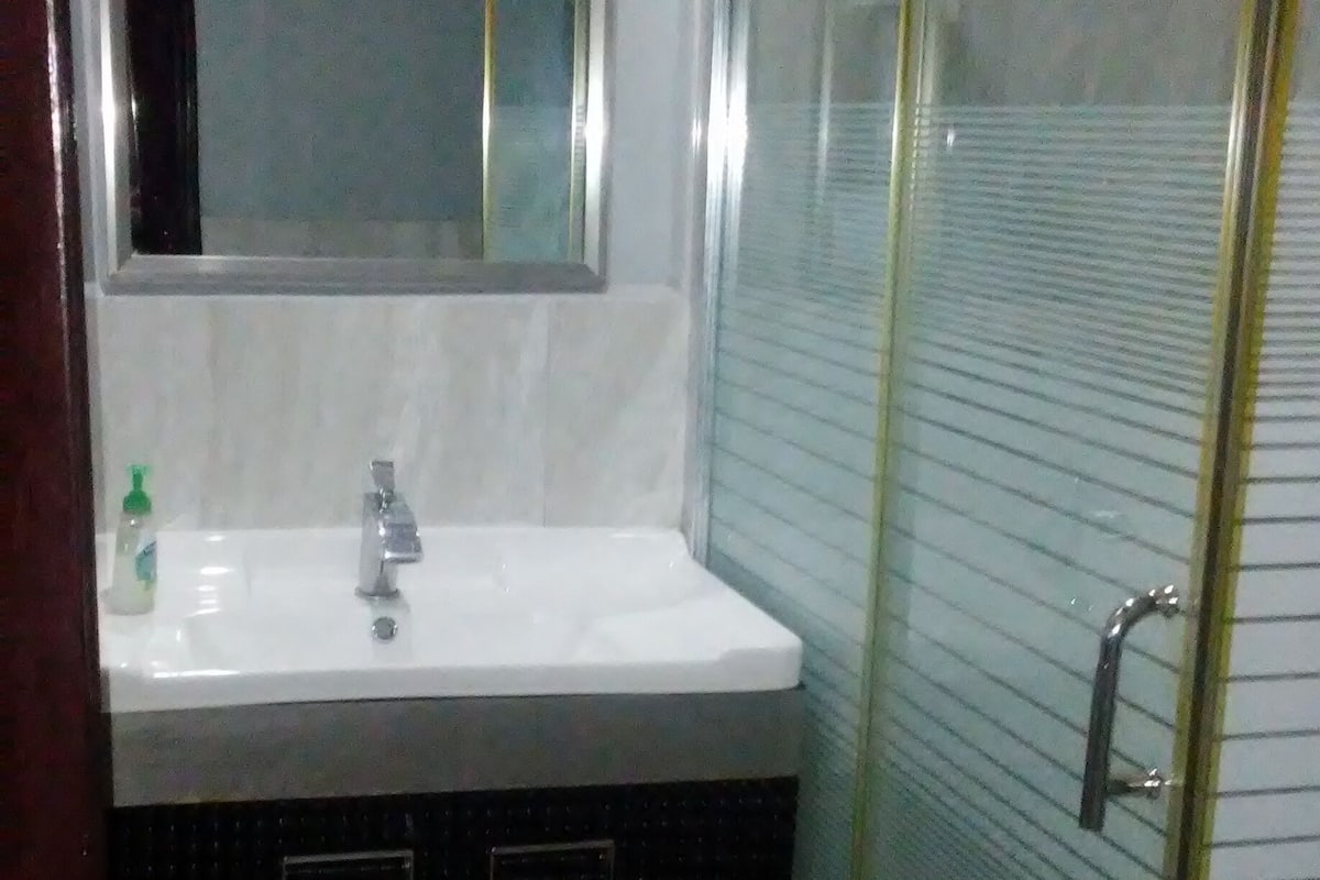 A bathroom with a white sink, a mirror, and a glass-enclosed shower.