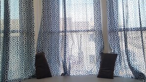 A seating area with a bench and patterned curtains. - DB Towers (Belize City)