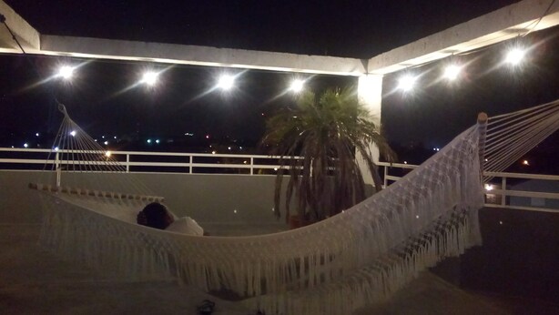 A hammock on a balcony with a view of the city at night. - DB Towers (Belize City)