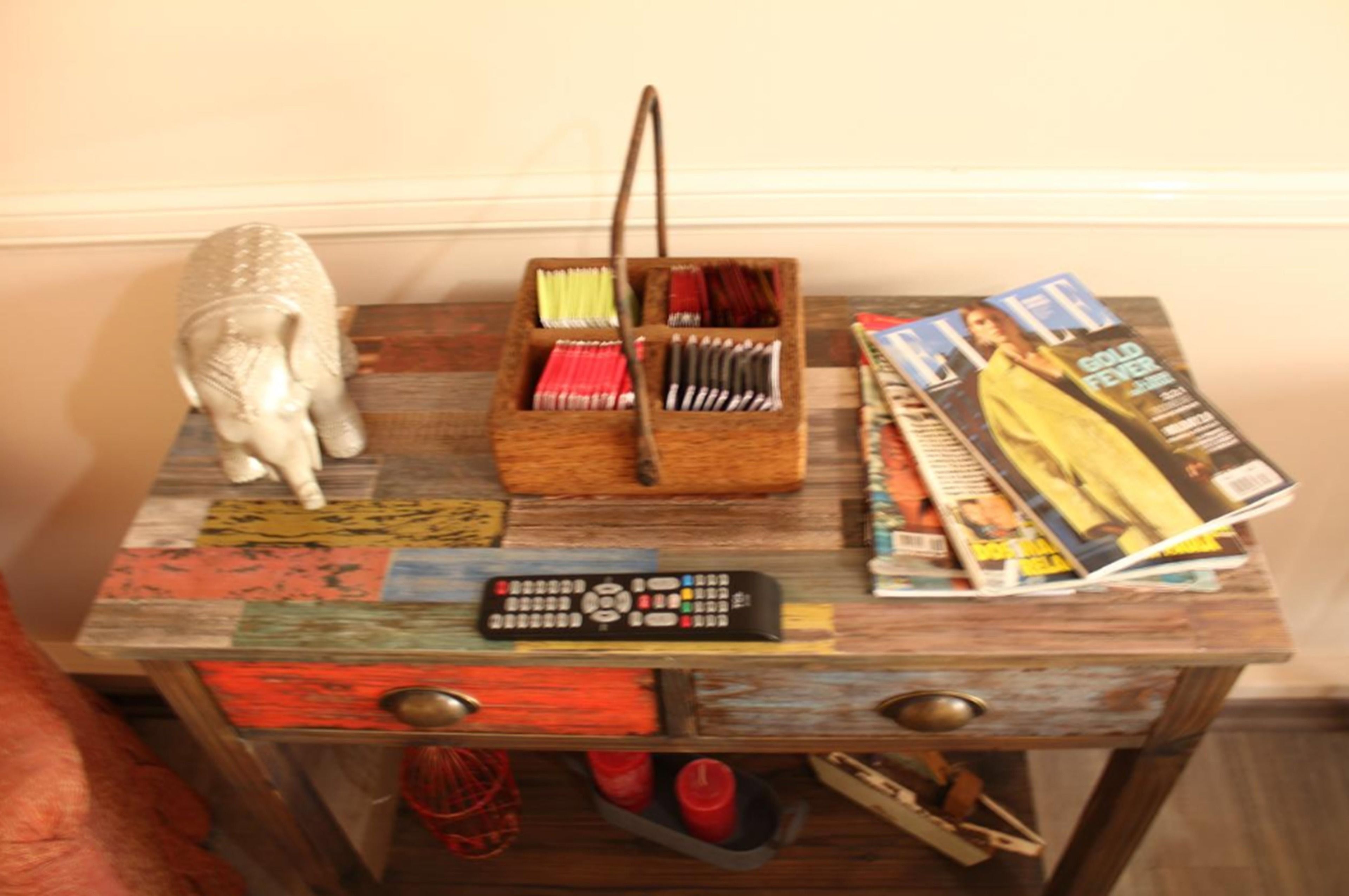 A wooden table with a remote control, a magazine, and a small statue.