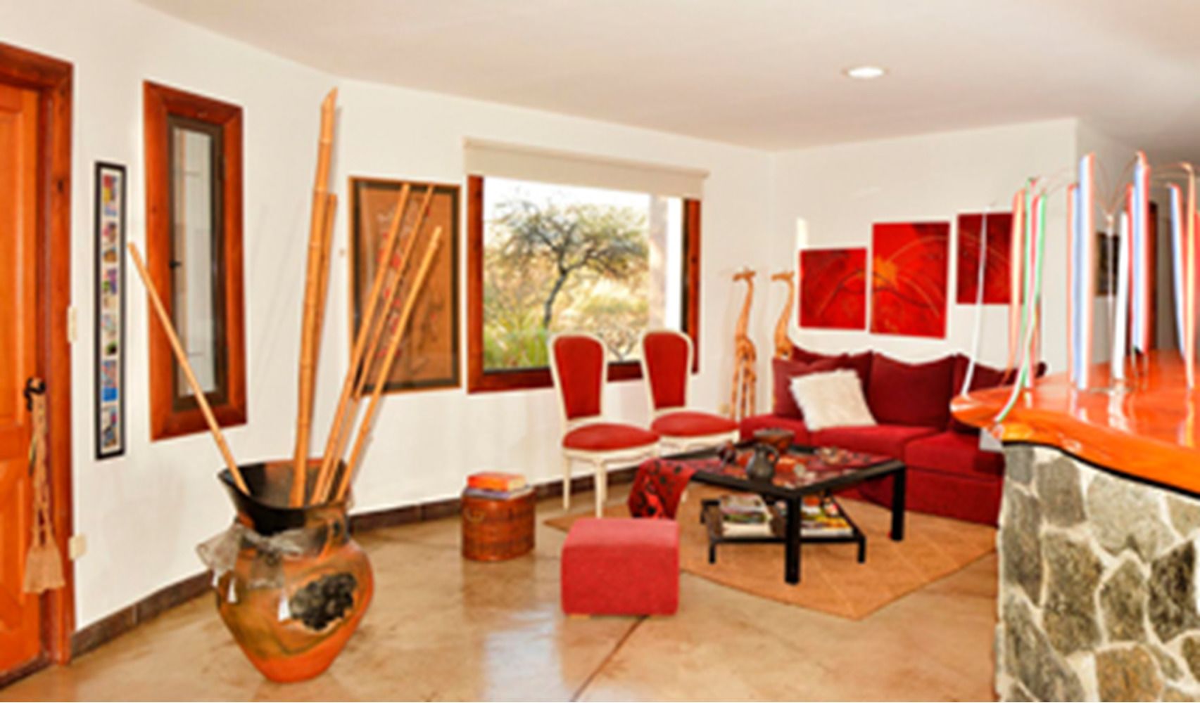 A living room with a red sofa, a coffee table, and a stone accent wall.