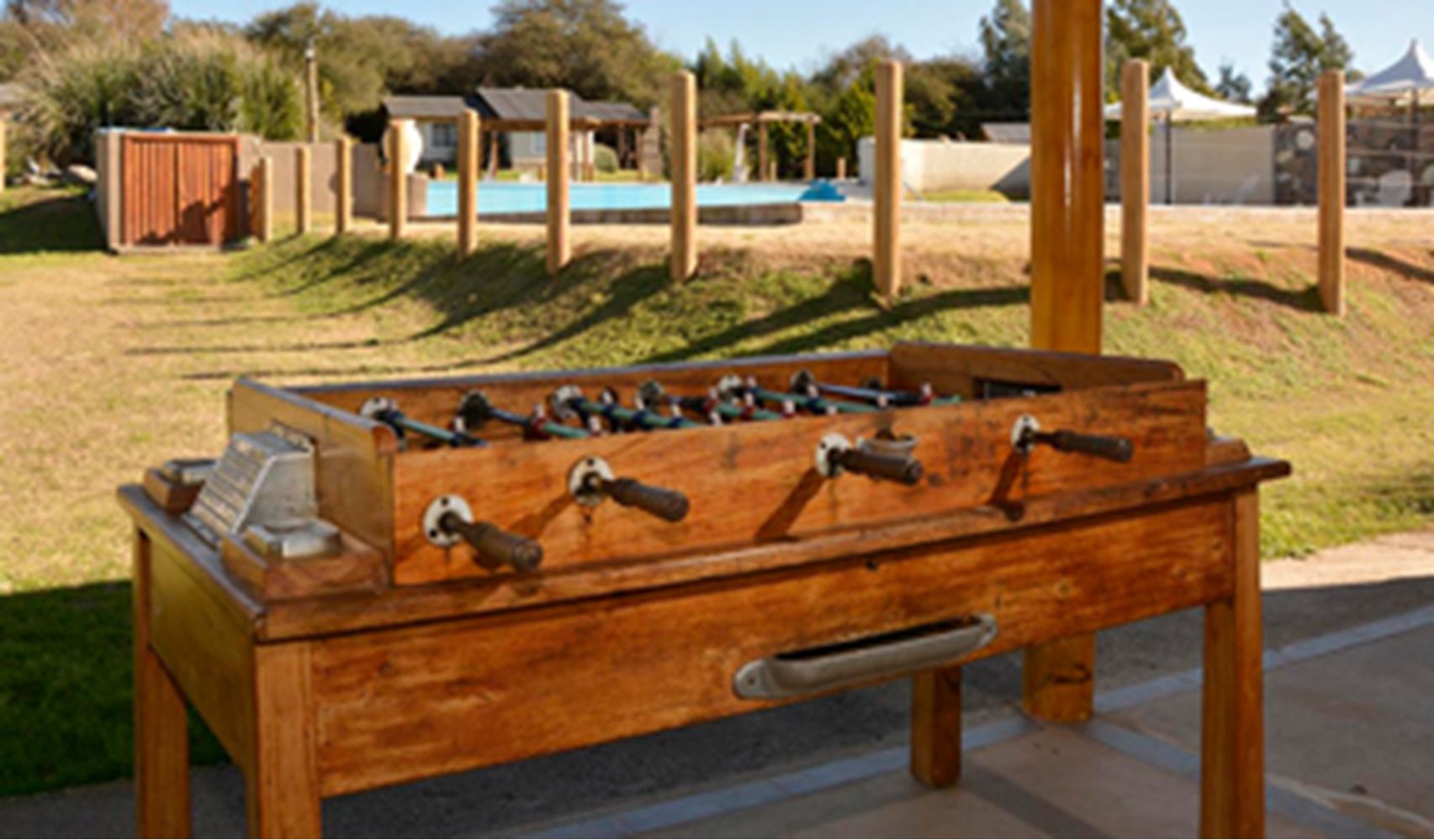 Une table de billard en bois, avec plusieurs queues et un porte-billes.