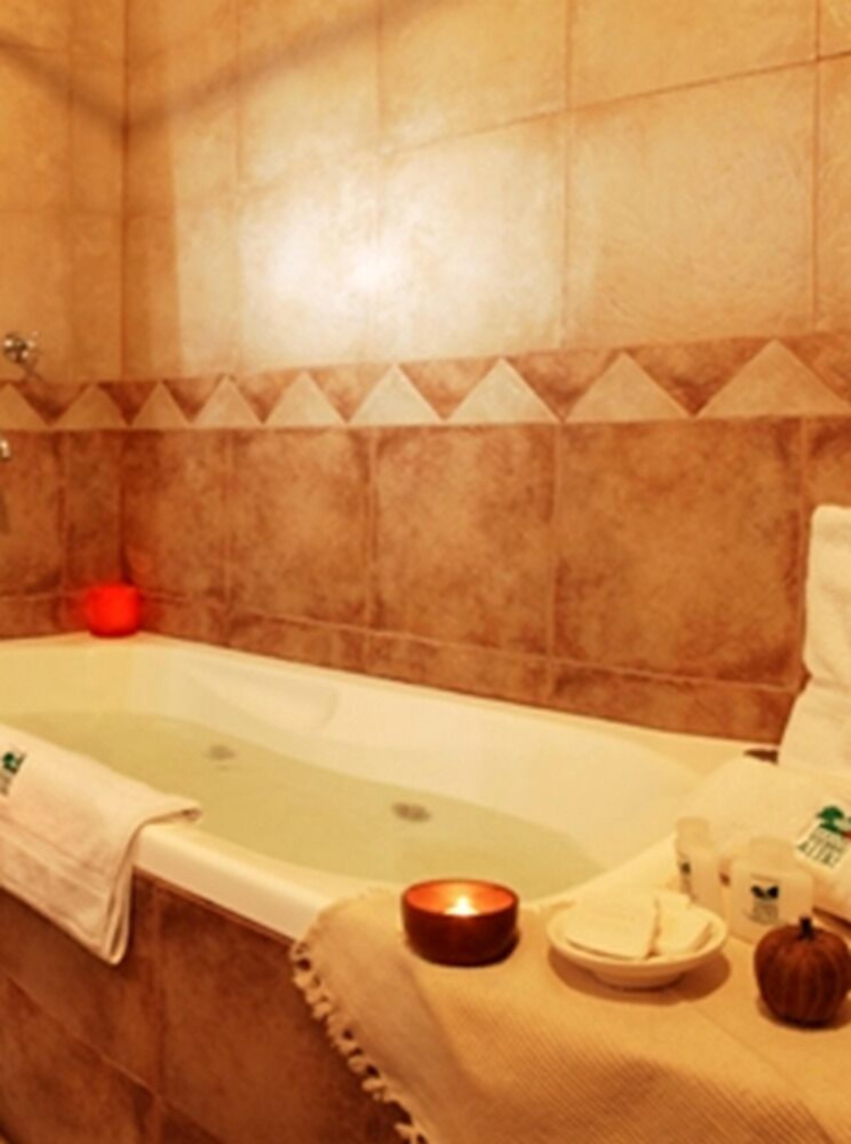 A bathroom with a bathtub, a towel, a candle, and a pumpkin.