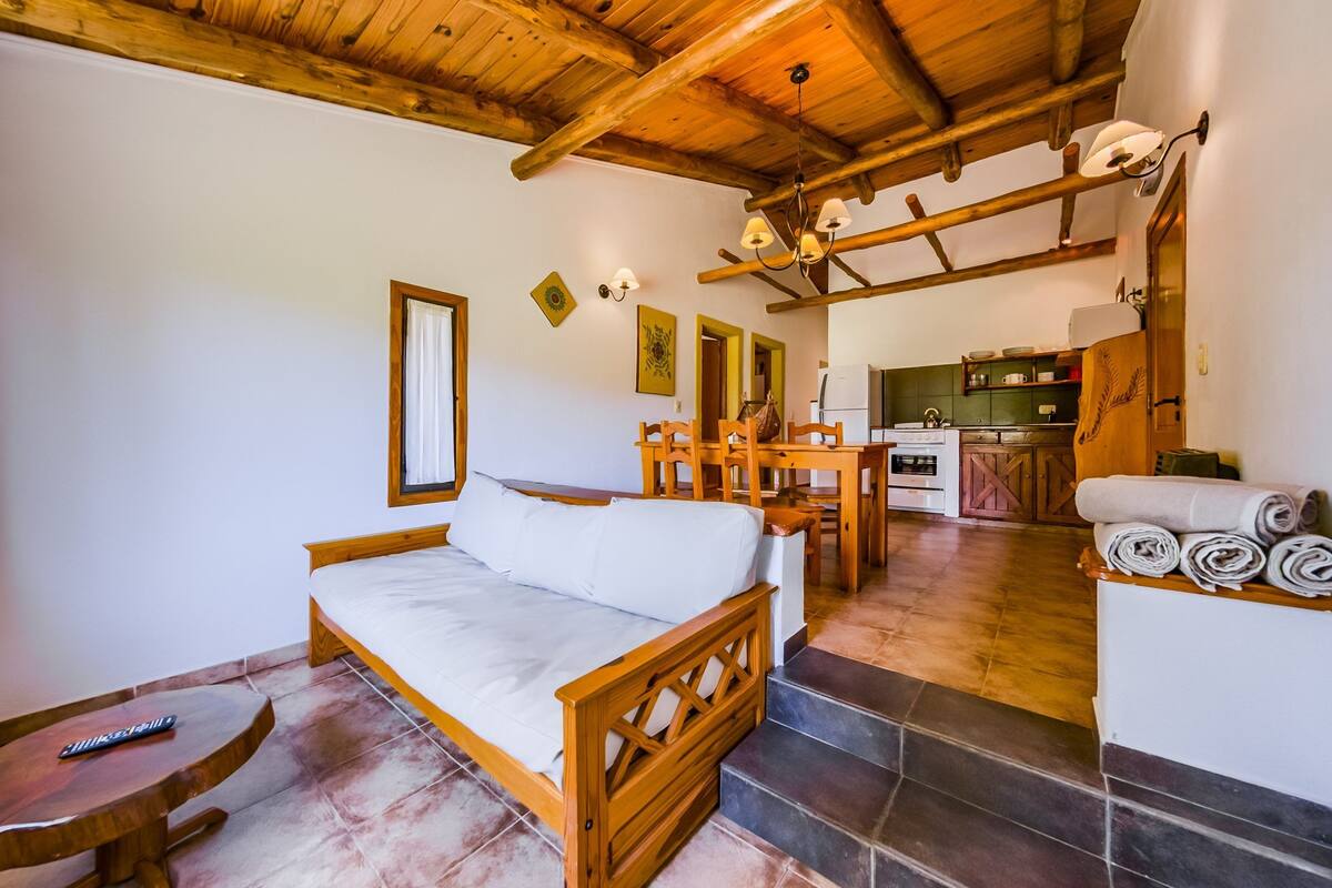 A cozy room with a wooden bed, a dining table, and a kitchen area.