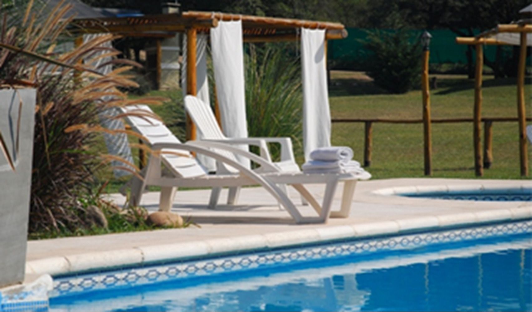 A pool area with lounge chairs and a small table with towels.