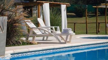 A pool area with lounge chairs and a small table with towels.
