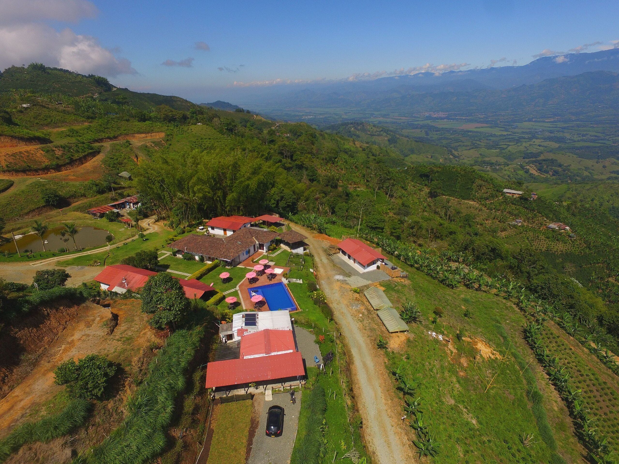 Una propiedad rural con varias construcciones, piscina y camino de tierra.