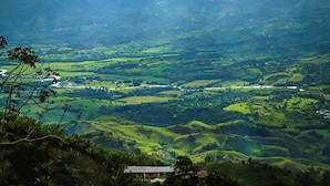 Una vista panorámica de un valle con colinas onduladas y un edificio pequeño al frente.