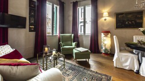Un salon chaleureux avec un fauteuil vert, un canapé, une table basse et un coin repas avec une table mise pour deux personnes.
