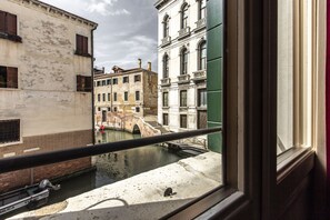 Blick auf einen Kanal von einem Fenster mit Balkon, mit historischen Gebäuden und einer Brücke.