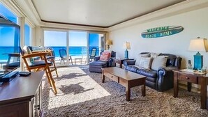A living room with a view of the ocean, a sofa, a coffee table, and a sign that reads "Beach Bums". - Ocean Front House with Private Ground Level Patio & 2 Garages - Sleeps 10+ (San Diego)