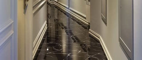 Un couloir doté d’un sol en marbre, de murs blancs et d’un éclairage encastré.