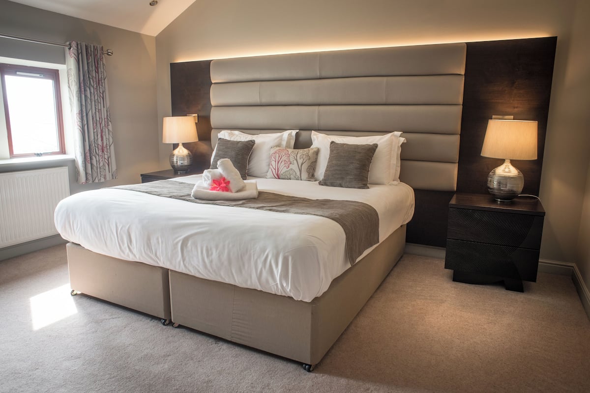 Un dormitorio moderno con una cama grande, dos mesitas de noche y una ventana con cortinas.