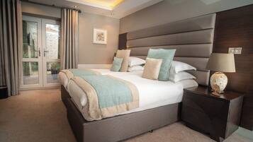 A bedroom with a large bed, a nightstand, a lamp, and a sliding glass door.