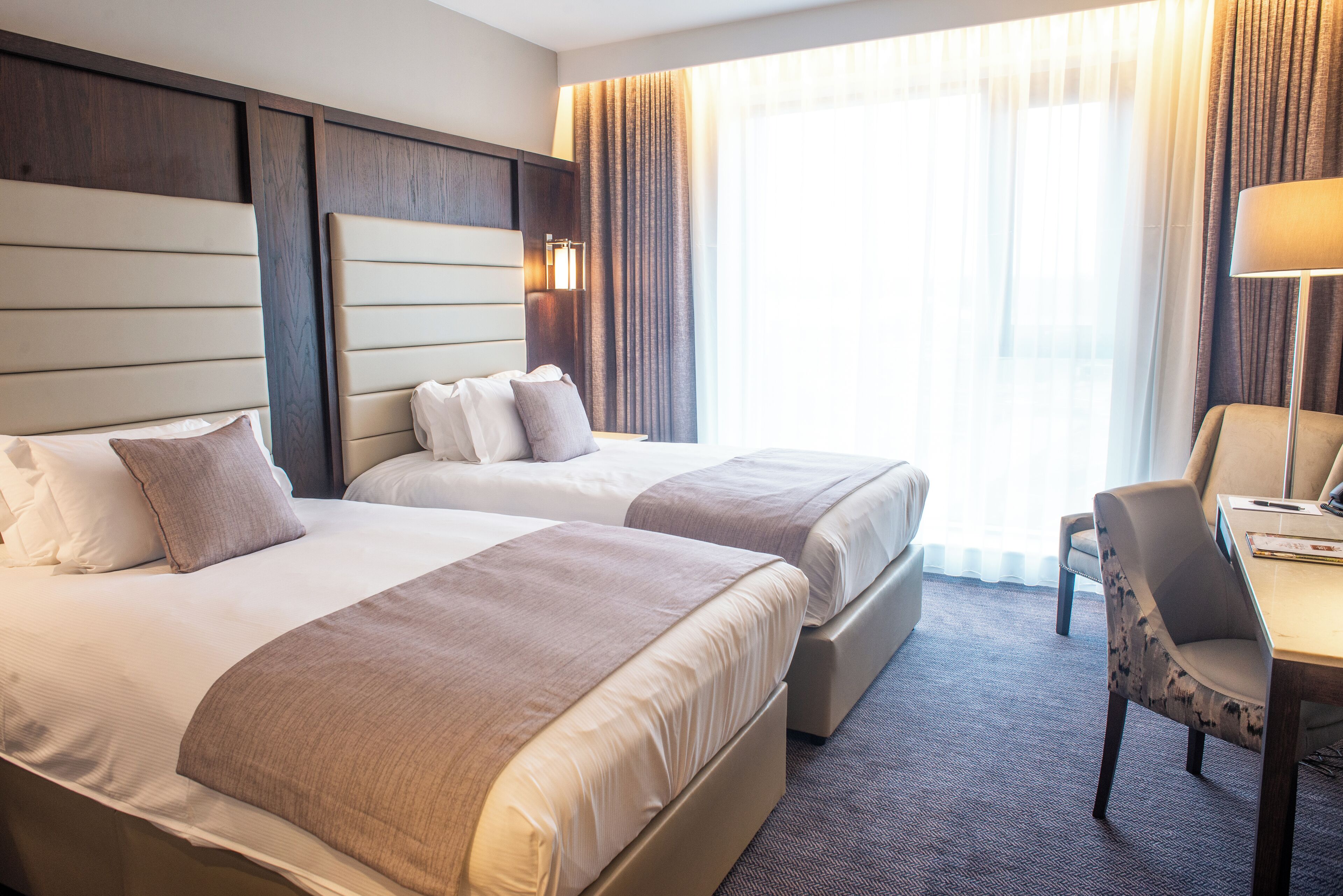 Habitación de hotel con dos camas, un escritorio y una silla.