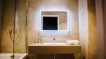 Un baño con bañera, lavabo y espejo con luz.
