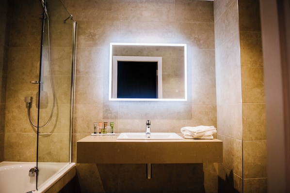 Une salle de bain avec une baignoire, un lavabo et un miroir avec un éclairage intégré.