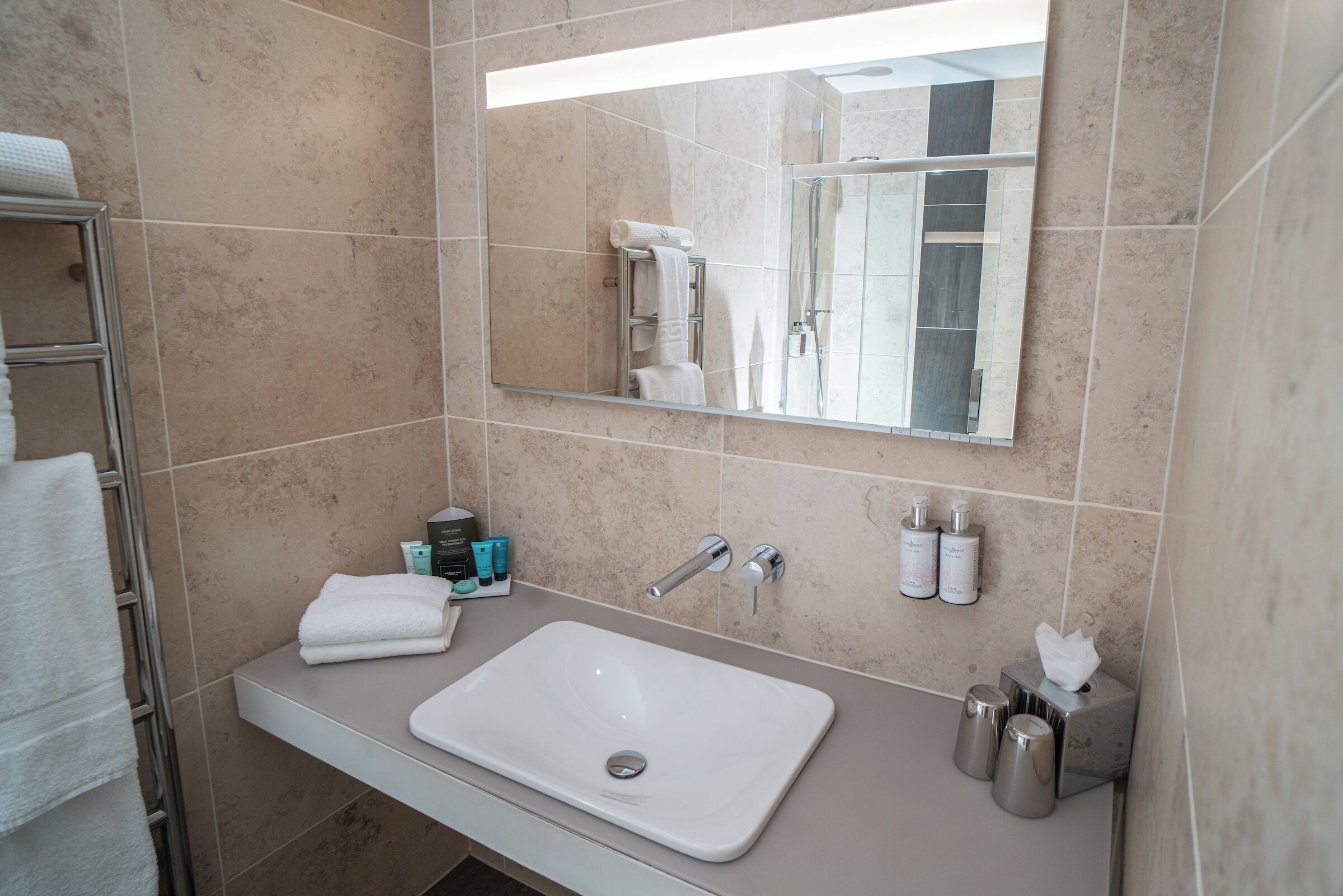A bathroom with a white sink, mirror, and towel rack.