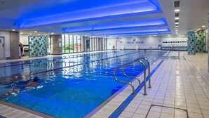 An indoor swimming pool with clear lane markings, a lifeguard chair, and a "CROW FOOD" sign on the wall.