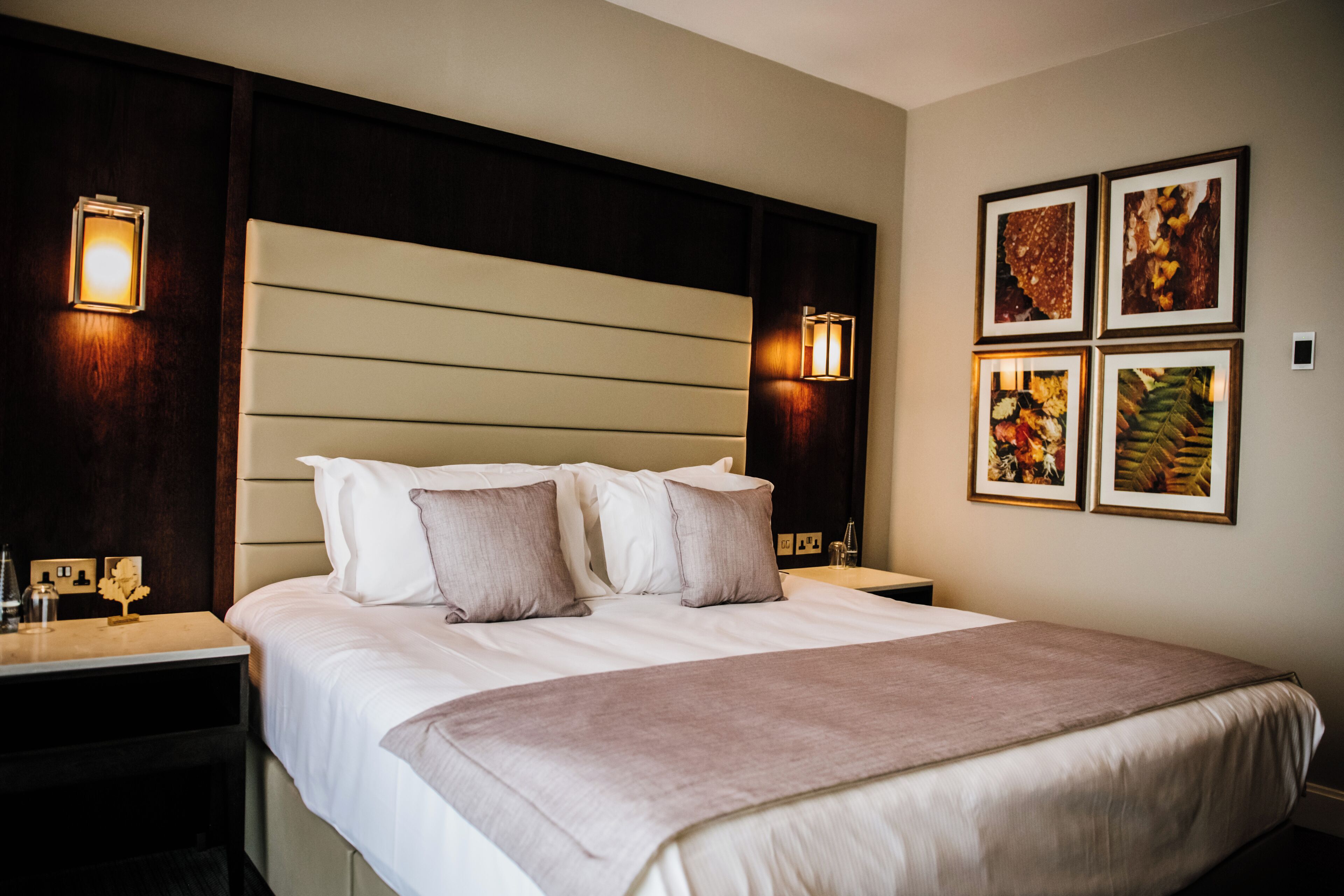 Een hotelkamer met een groot bed, twee nachtkastjes en wandlampen.