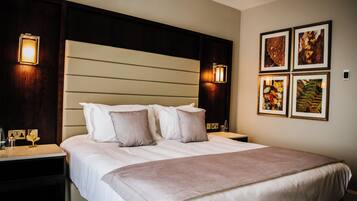 Een hotelkamer met een groot bed, twee nachtkastjes en wandlampen.