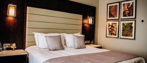 Een hotelkamer met een groot bed, twee nachtkastjes en wandlampen.