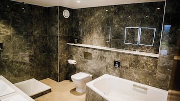 A modern bathroom with a large bathtub, a toilet, and a shower area.