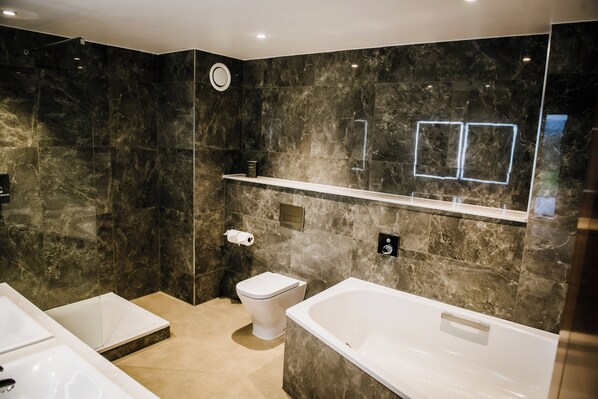 Une salle de bain moderne avec une grande baignoire, des toilettes et un espace douche.