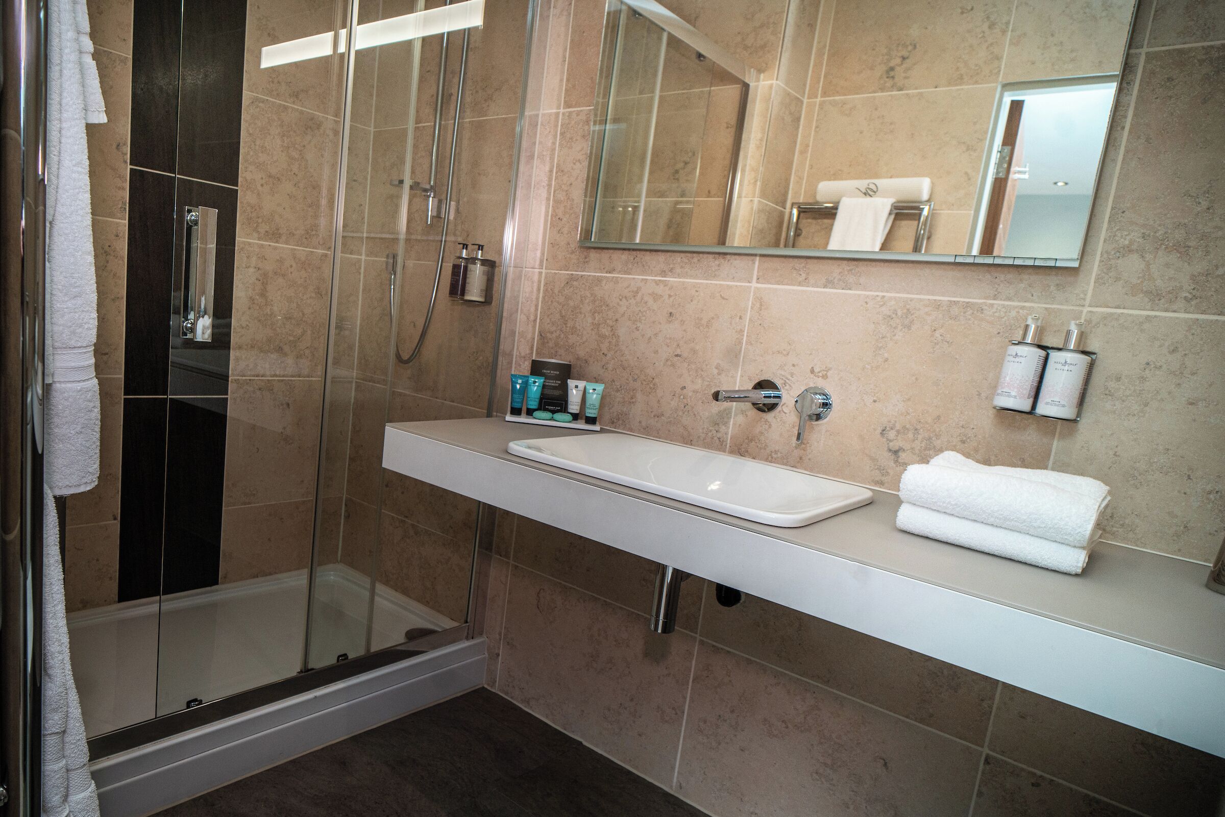 A modern bathroom with a glass-enclosed shower, a white sink, and a large mirror.