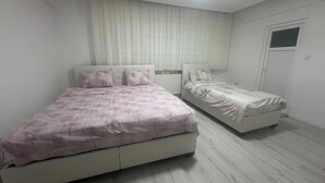 Una camera da letto con due letti, una finestra con tende e una porta.