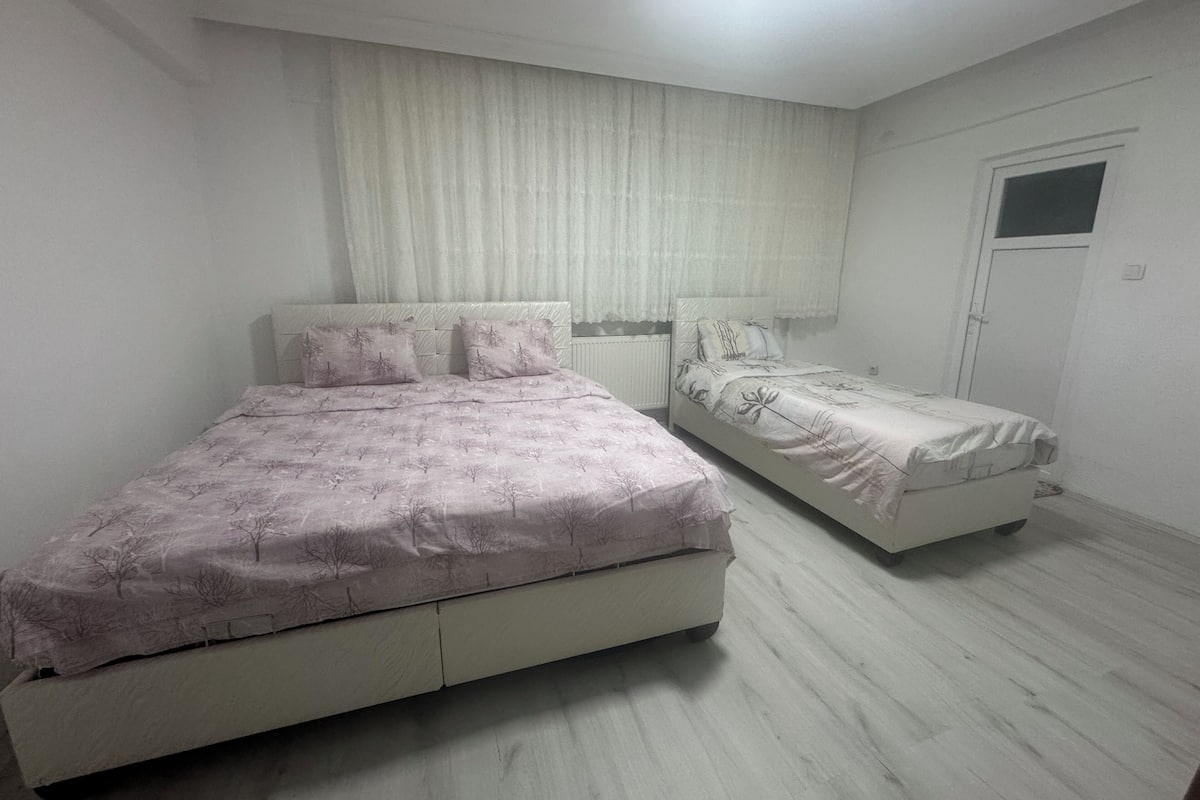 Une chambre avec deux lits, une fenêtre avec des rideaux et une porte.