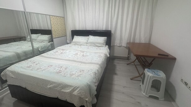 Una camera d'albergo con due letti, un tavolino, uno sgabello e un termosifone.