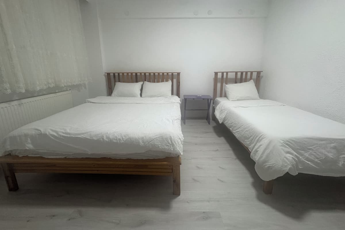 Une petite pièce propre, avec deux lits en bois, une table de chevet et un radiateur.