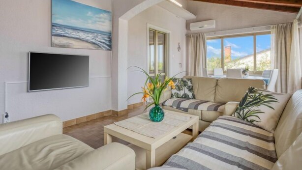 Een woonkamer met een bank, een salontafel, een televisie en een schilderij aan de muur.