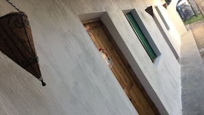 Un couloir étroit aux murs blancs et une porte en bois.