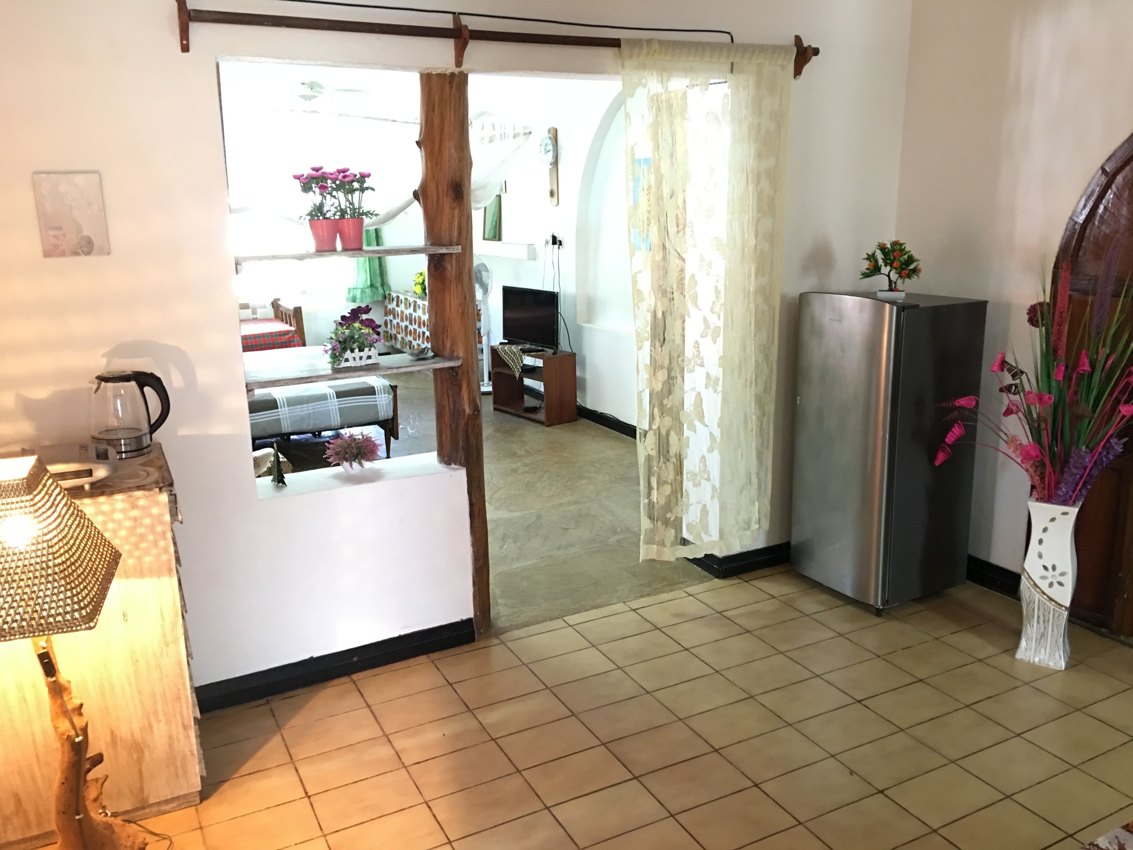 Une cuisine équipée d’un réfrigérateur, d’une machine à café et d’une plante en pot.