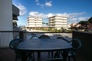 A balcony with a table and chairs, overlooking a building with multiple balconies and a clear sky. - M089 - Marcelli, three-room apartment with terrace 30 meters from the sea (Marcelli)