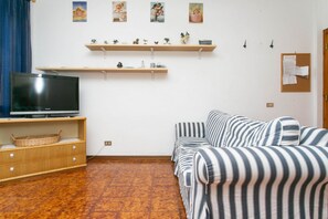 A living room with a TV, sofa, wooden shelves, and artwork on the wall. - M089 - Marcelli, three-room apartment with terrace 30 meters from the sea (Marcelli)