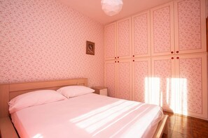 A bedroom with a bed, a nightstand, a wardrobe, and a picture on the wall.