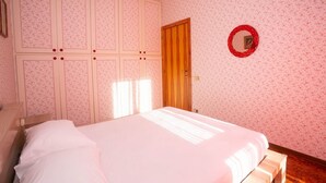 Ein Schlafzimmer mit einem Bett, einem Kleiderschrank und einem Spiegel an der Wand.