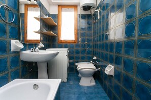 Et badeværelse med vask, toilet og badekar.