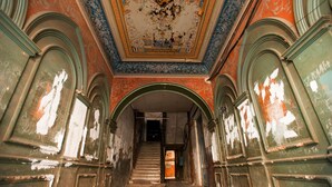 Eine prächtige Treppe mit aufwendigen Verzierungen und einer beschädigten Decke.