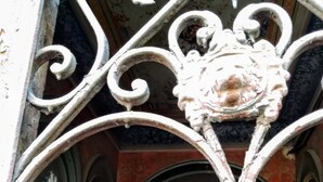 Eine kunstvolle Metalltreppe mit Verzierungen an der Brüstung führt in einen dunklen Innenraum.