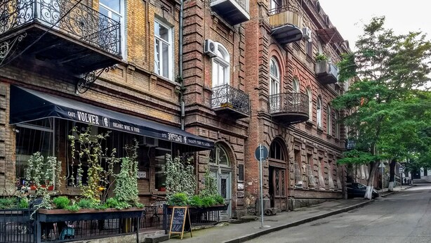 Ein historisches Gebäude mit einem Café namens 'Cafe Volver' im Erdgeschoss, mit Außenplätzen und Pflanzen.