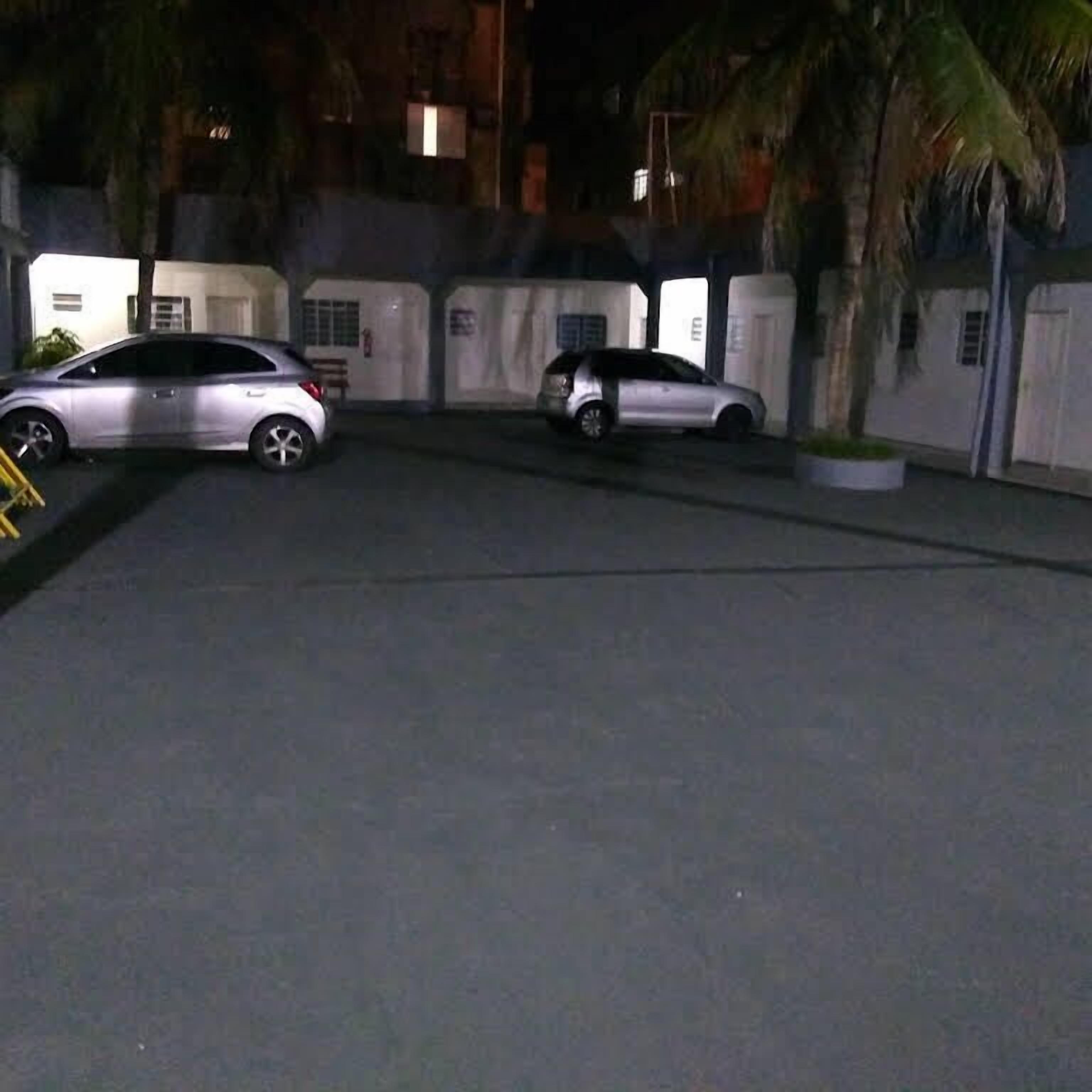 A parking area with two cars parked, surrounded by buildings with gated entrances.