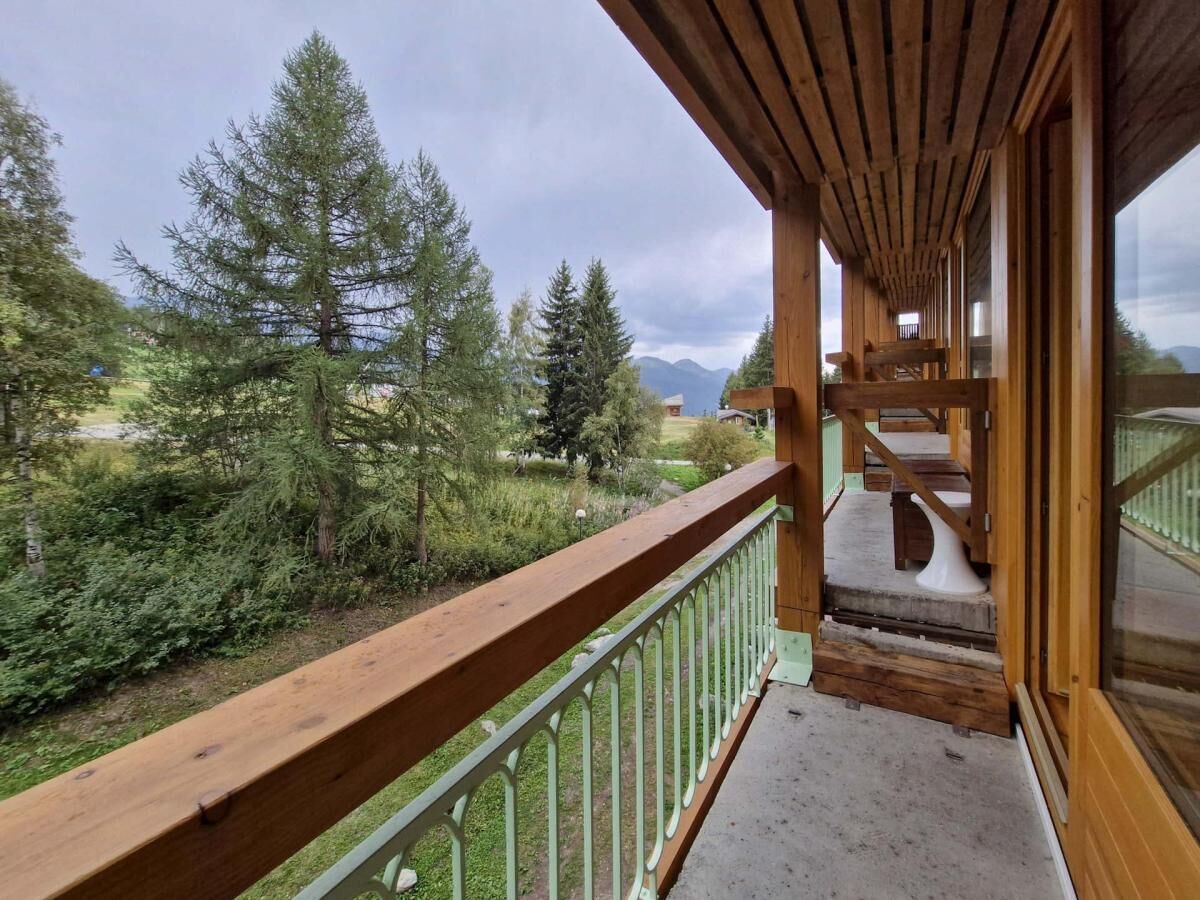 A wooden balcony with a view of a forest and mountains.